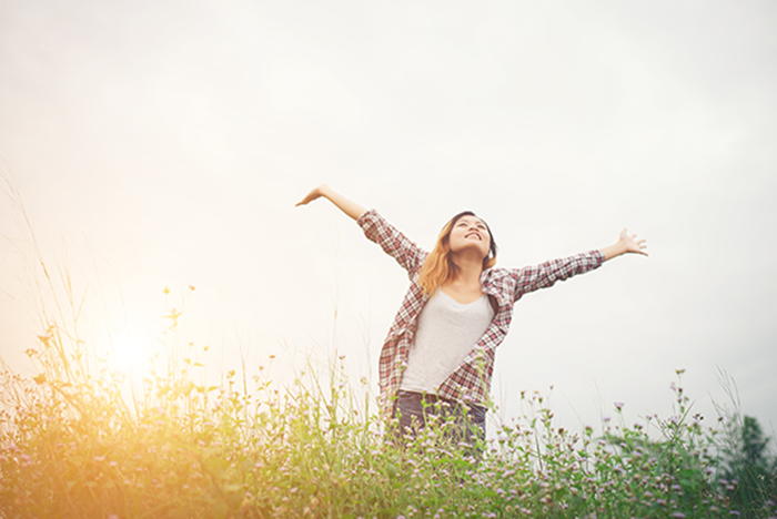 Young beautiful hipster woman in a flower field at sunset. Freed