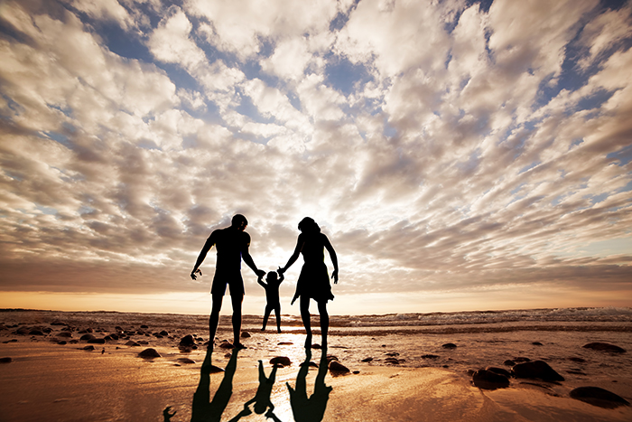 Happy family together hand in hand on the beach at sunset. Summe